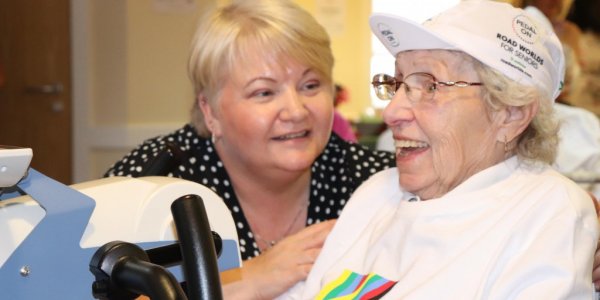 Two ladies chatting whilst one is on an exercise bike