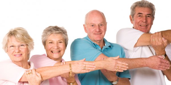 Two women and two men standing in a row stretching their right arm