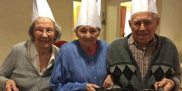 Three residents holding frying pan and pancake