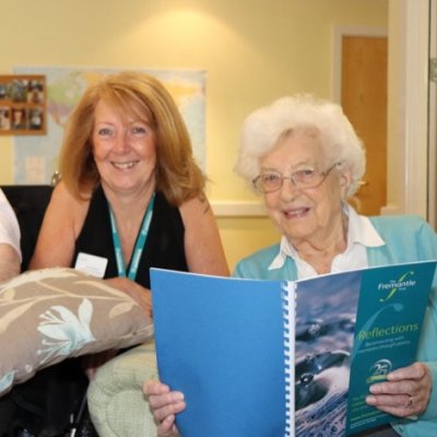 Residents reading the Reflections poetry book with Leisure and Lifestyle manager Sue Faulkner
